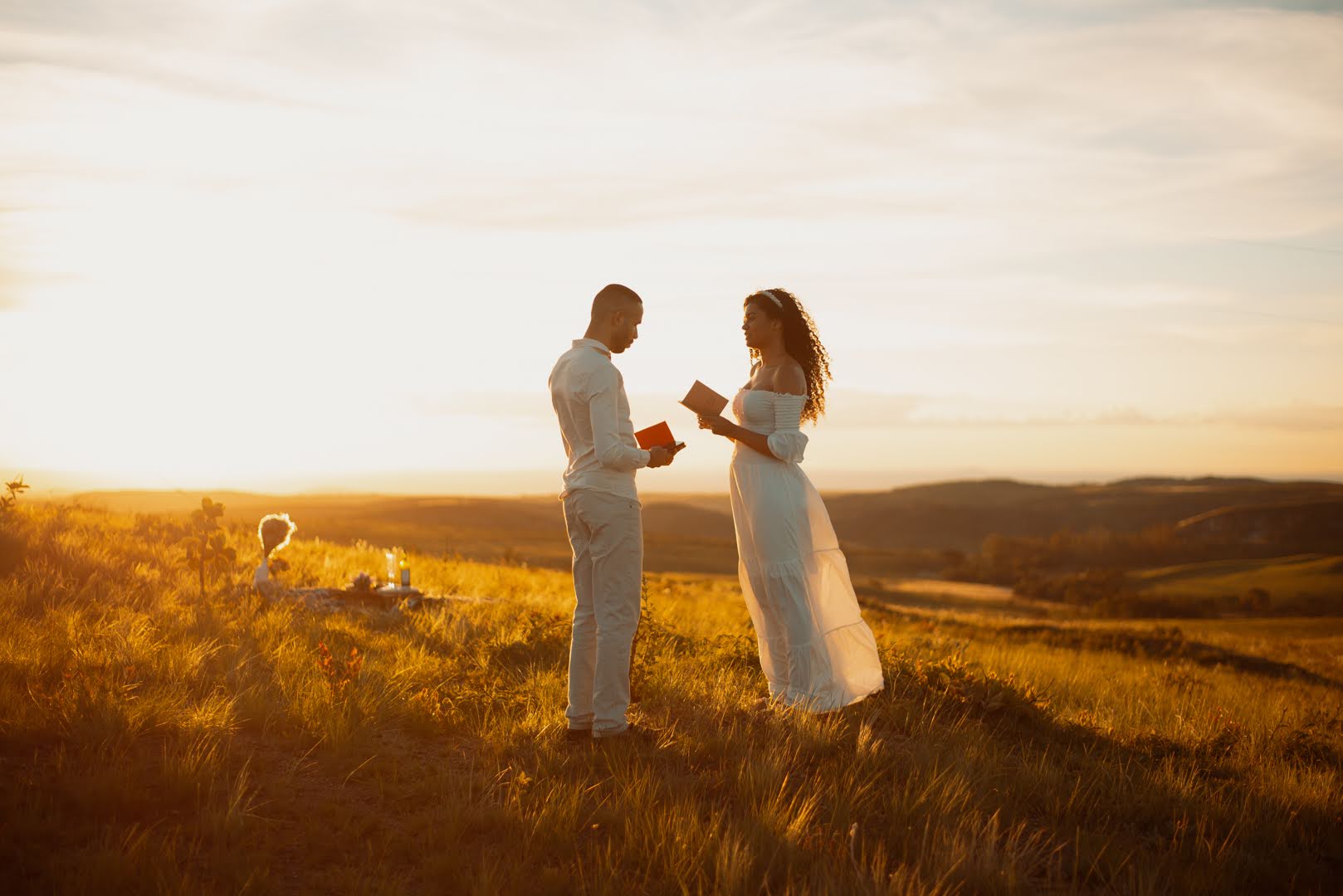 Casal trocando votos ao pôr do sol no campo